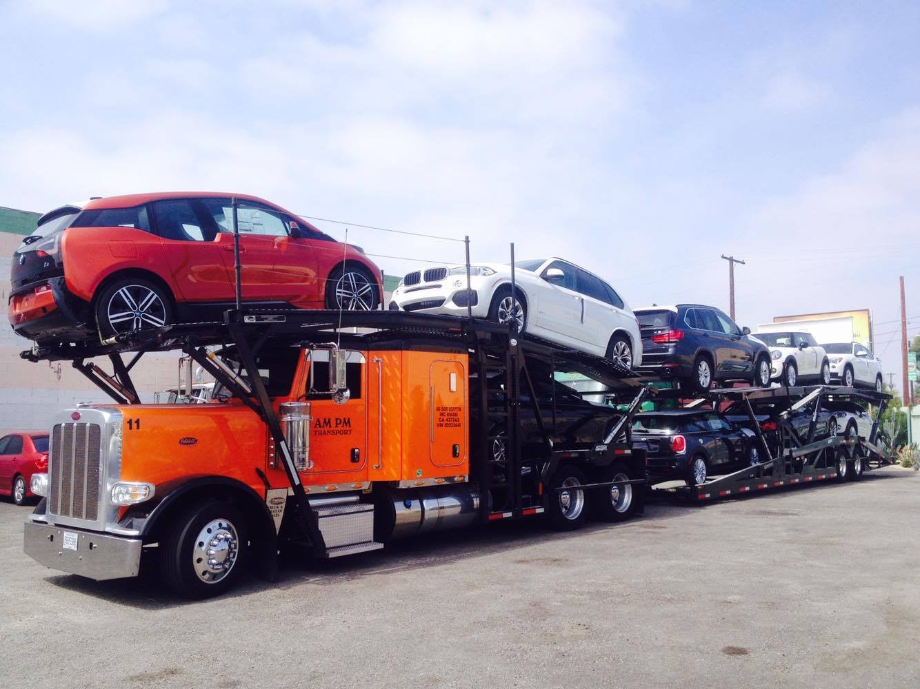 orange open hauler loaded with SUV multi color cars